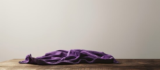 Sticker - A purple cloth or towel lies on a brown table, isolated against a white backdrop with a copy space image.