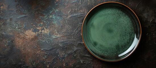 Canvas Print - Top view of an empty classic green plate on a dark rough table surface with ample copy space for menu or recipe backgrounds, enhancing a rustic table setting.