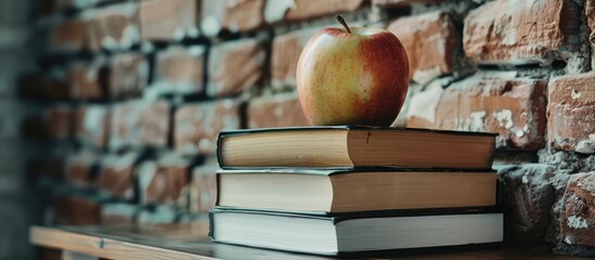 Poster - Education concept depicted by textbooks and an apple on a desk against a school brick wall background, including copy space image.