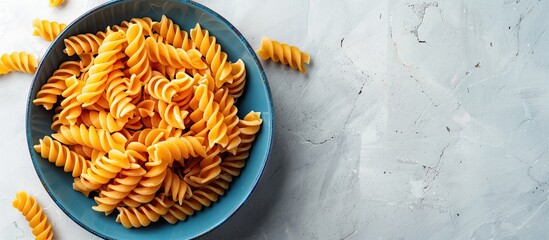 Aufkleber - Ample copy space surrounds a vibrant array of spiral pasta in a blue bowl placed on a white surface.