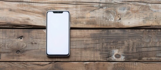 Poster - Smartphone with a white exterior laid on a wooden surface with a clear area for additional content in the photograph - a copy space image.