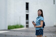 © Wasana - A young woman wearing a blue shirt and blue skirt is holding a book and smiling