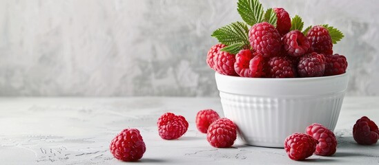 Poster - A white ceramic bucket with fresh raspberries on a light background featuring copy space image