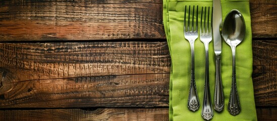 Poster - A place setting featuring silverware on a green napkin over a wooden surface with room for a copy space image