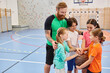 © LIGHTFIELD STUDIOS - A man stands in front of a diverse group of kids on a basketball court, instructing them on proper techniques and strategies.