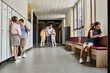 © LIGHTFIELD STUDIOS - group of children stand in hallway beside lockers while a teacher instructs them in a bright, lively classroom setting.