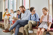 © LIGHTFIELD STUDIOS - group of kids and adult teacher sitting, chatting, and listening attentively on a bench in a lively and colorful classroom setting.