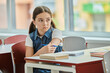 © LIGHTFIELD STUDIOS - A young girl sits at a table engrossed in a book, absorbing knowledge in a bright, lively classroom setting.