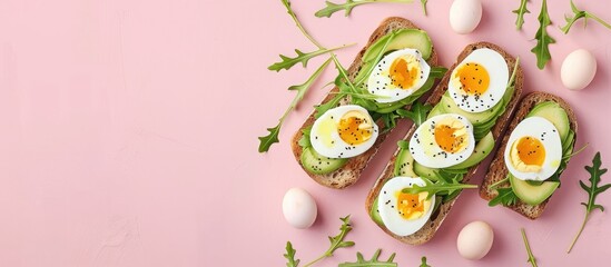 Aufkleber - Delicious sandwiches featuring avocado arugula boiled eggs and mozzarella cheese on fried toast displayed on a pink background with a perfect copy space image