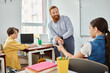 © LIGHTFIELD STUDIOS - A man stands before a desk, passionately teaching children in a vibrant classroom setting.