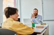 © LIGHTFIELD STUDIOS - A man sits attentively at a desk, engaged in conversation with a child.