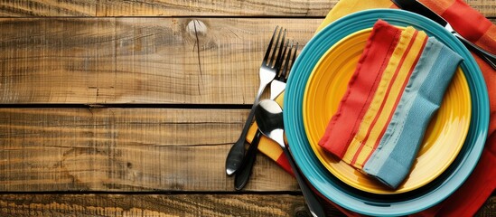 Leinwandbilder - Top down view of a restaurant menu setting featuring an empty plate cutlery and colorful napkin on a wooden background designed with copy space image