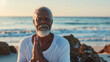 © KotBaton - Focused older African American man practicing yoga and posing on the beach with copy space.