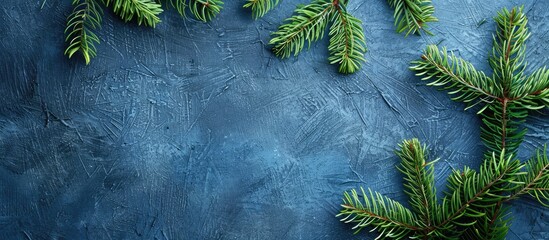 Poster - Christmas themed background with green fir branches on a textured blue surface ideal for adding text copy space image