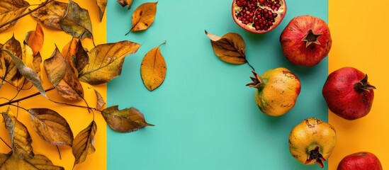 Poster - Autumn themed border arrangement with pomegranates dry leaves on a yellow green backdrop Creative flat lay top view with a copy space image