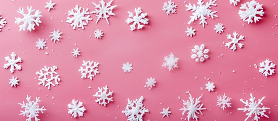 Poster - Christmas themed white snowflakes decorating a pink background create a festive copy space image as a flat lay