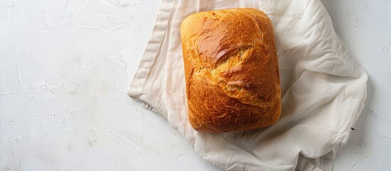 Poster - Top view of a healthy white bread loaf with a napkin on a white background creating a visually appealing copy space image