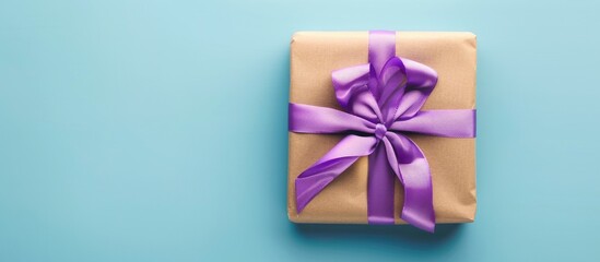 Aufkleber - Top view of a gift box wrapped in paper with a purple ribbon displayed on a colored table with a blue background for a copy space image