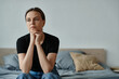 © LIGHTFIELD STUDIOS - Middle-aged woman sitting on bed, deep in thought, hand on chin.