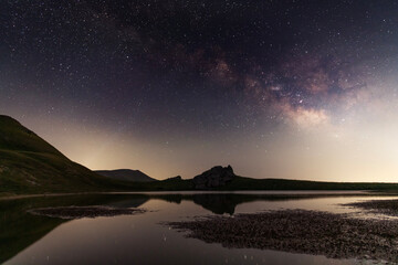 Wall Mural - beautiful night landscape, small lake in the mountains under bright milky way galaxy.