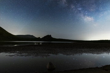 Wall Mural - beautiful night landscape, small lake in the mountains under bright milky way galaxy.