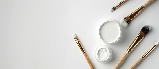 Poster - top down view of a pot of white paint and brushes on a blank background with copy space image
