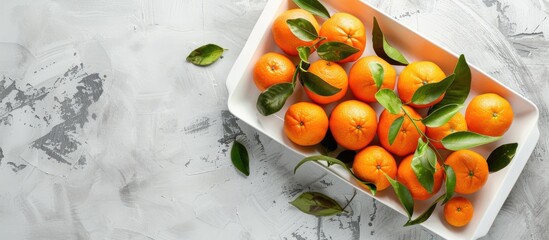 Sticker - Top view of fresh organic tangerines placed in a white wooden tray on a light concrete background with space for additional images or text