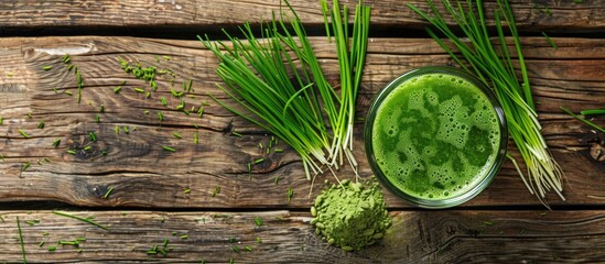 Poster - View from above of a glass of fresh wheatgrass juice and powder on a wooden surface with a blank space for an image. Copy space image. Place for adding text and design