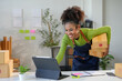 © amnaj - Woman in her home office using a digital tablet to prepare packages for delivery and manage her online business