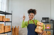 © amnaj - Warehouse employee holds cardboard boxes and gestures upwards with her index finger, indicating a brilliant business idea