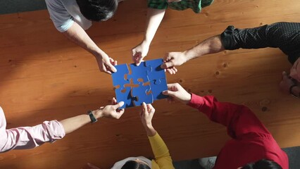 Wall Mural - Top down view of skilled business people assemble blue jigsaw puzzle on meeting table. Group of diverse team working together to solve the puzzle. Represented togetherness, cooperative. Convocation.