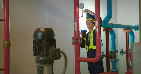 Canvas Print - Professional engineer worker man in safety uniform holding flashlight checking maintenance the industry pipeline pump system construction under the building factory