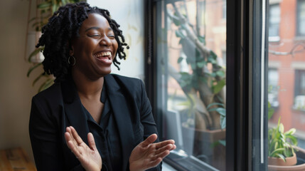 Sticker - A joyful individual, laughing and clapping, sits by a window with plants and urban scenery in the background, emanating warmth and happiness.