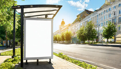 Vertical blank glowing billboard on the city street. In the background buildings and road with cars. Mock up. The poster on the street next to the roadway.