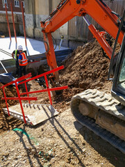 Construction site with workers building a house extension, installing foundations, steel reinforcement, and concrete footings. Urban construction process for residential development. 