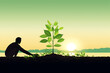 © fathiyehki - A silhouette of a man planting a green tree at sunset, symbolizing hope, growth, and new beginnings.