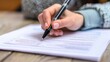 © Nicholas - A close-up view of a hand signing an official document with a black pen, highlighting the importance of formal agreements and the responsibility of signing legal papers.