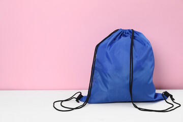 Canvas Print - Blue drawstring bag on white wooden table against pink background. Space for text