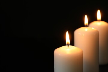 Wall Mural - Many burning candles on black background, closeup. Space for text