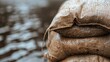© familymedia - A close-up shot of a sandbag partially submerged in floodwater, with detailed texture and visible stitching, emphasizes the essential role of such barriers in flood situations.