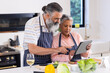 © WavebreakMediaMicro - Cooking together, senior couple using tablet for recipe in modern kitchen