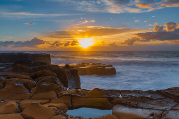 Sunrise, sea, waves, clouds and tessellated rock platform