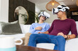 © Wavebreak Media - Using VR headsets, male gay couple laughing and enjoying virtual reality at home