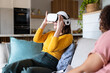 © Wavebreak Media - Using VR headset, woman sitting on couch and enjoying virtual reality experience