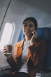 © ARMMY PICCA - Traveling and technology. Flying at first class. Pretty young businees woman using smartphone while sitting in airplane.