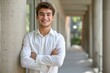 © senyumanmu - Young smiling business university student standing against college campus wall with arms crossed