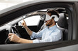 © sofiko14 - Man wearing VR headset sitting inside car exploring virtual reality technology. Concept of immersive experience and advanced innovation in automotive industry.