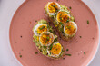 © Wavebreak Media - Avocado toast with boiled eggs and spices on pink plate, garnished with chives, copy space