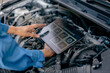 © sirichai - Automotive mechanic repairman using tablet to checking engine room, check the mileage of the car, oil change, car auto service, auto maintenance service concept.
