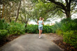 © Brocreative - Beautiful middle-aged woman going on a run outdoors along a paved path in Florida, USA. Adult female working to stay fit and healthy in 40s.